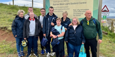 A group from Mountfern during their visit to Rathlin Island, with a sign in the background about the seabird centre.