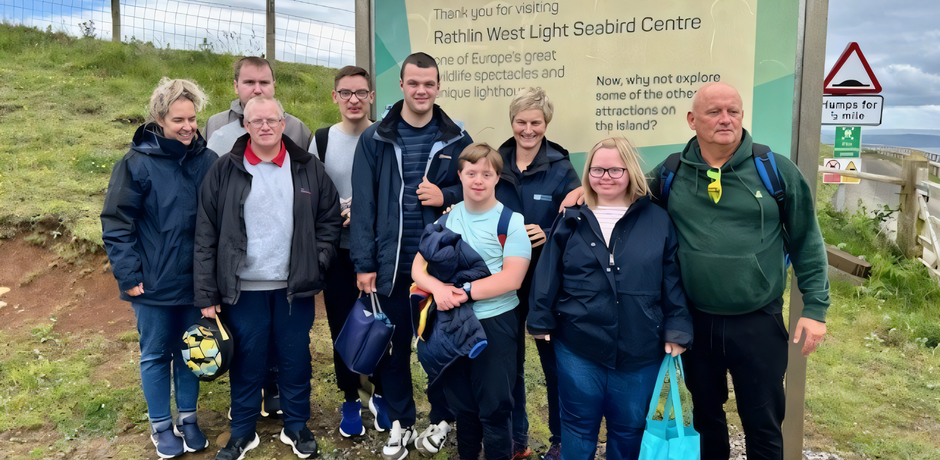 A group from Mountfern during their visit to Rathlin Island, with a sign in the background about the seabird centre.