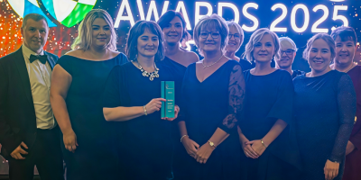 A group of people standing together. One is holding an award.
