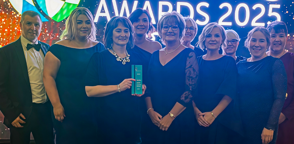 A group of people standing together. One is holding an award.