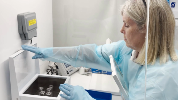 Marie Harvey, Lead Radiographer for Nuclear Medicine, wearing PPI, with a box in front of her with vials inside.