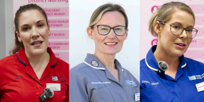 Three nurses - one is wearing a red tunic, one is wearing grey and the third is wearing blue.