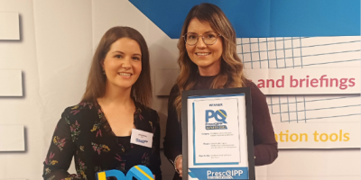 Two women standing together, one is holding a framed certificate.