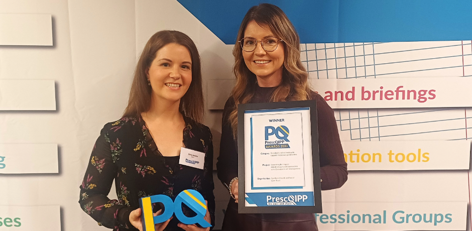 Two women standing together, one is holding a framed certificate.