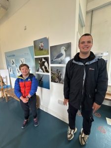 Two service users with wildlife posters on the wall behind them.