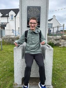 A service user from Mountfern sits on a stone chair on Rathlin Island.