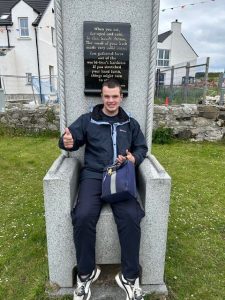 A service user from Mountfern sits on a stone chair on Rathlin Island.