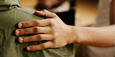 A hand resting on a shoulder. No faces are visible