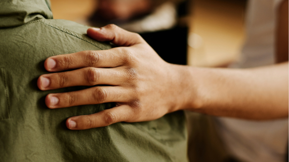 A hand resting on a shoulder. No faces are visible
