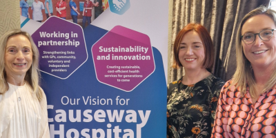 Group of three ladies standing on front of Causeway Hospital banner