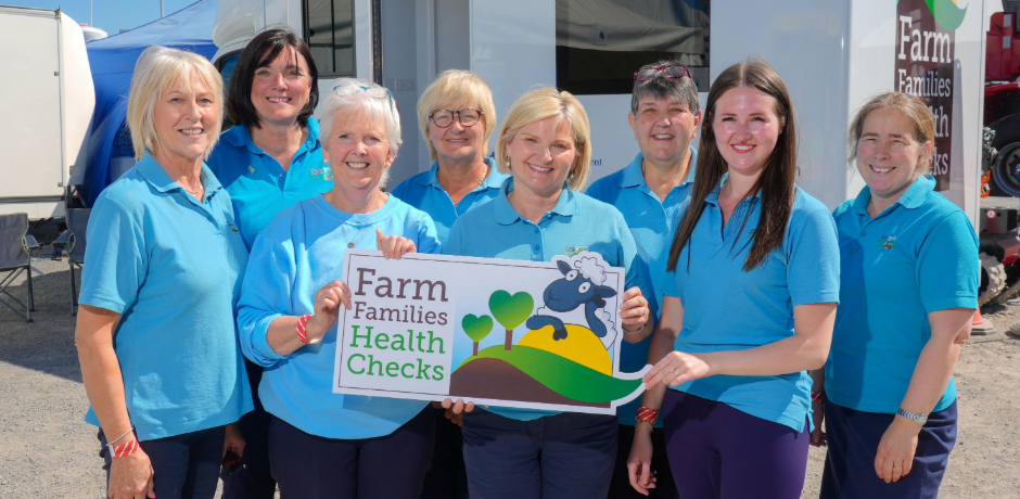 Eight members of the Farm Families Health Checks Team, holding a sign which reads 'Farm Families Health Checks'