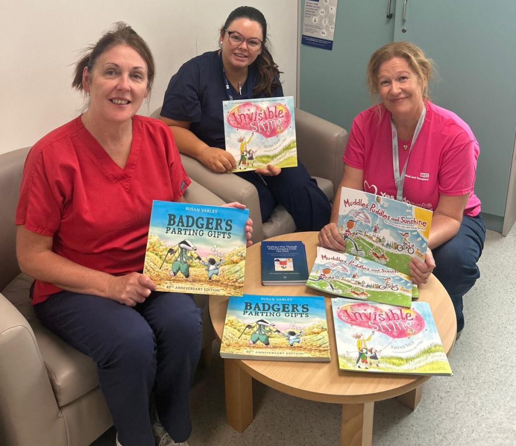 Three healthcare workers sitting together, holding books.