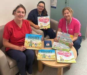 Three healthcare workers sitting together, holding books.