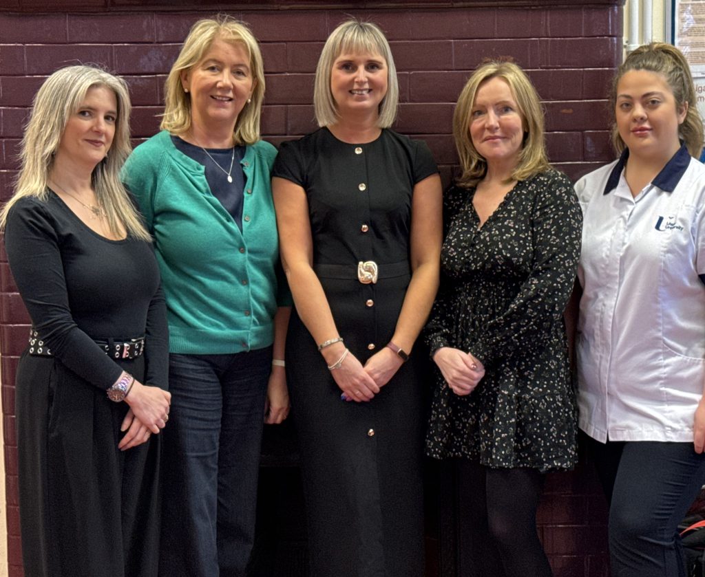 Group of five women standing in front of a wall