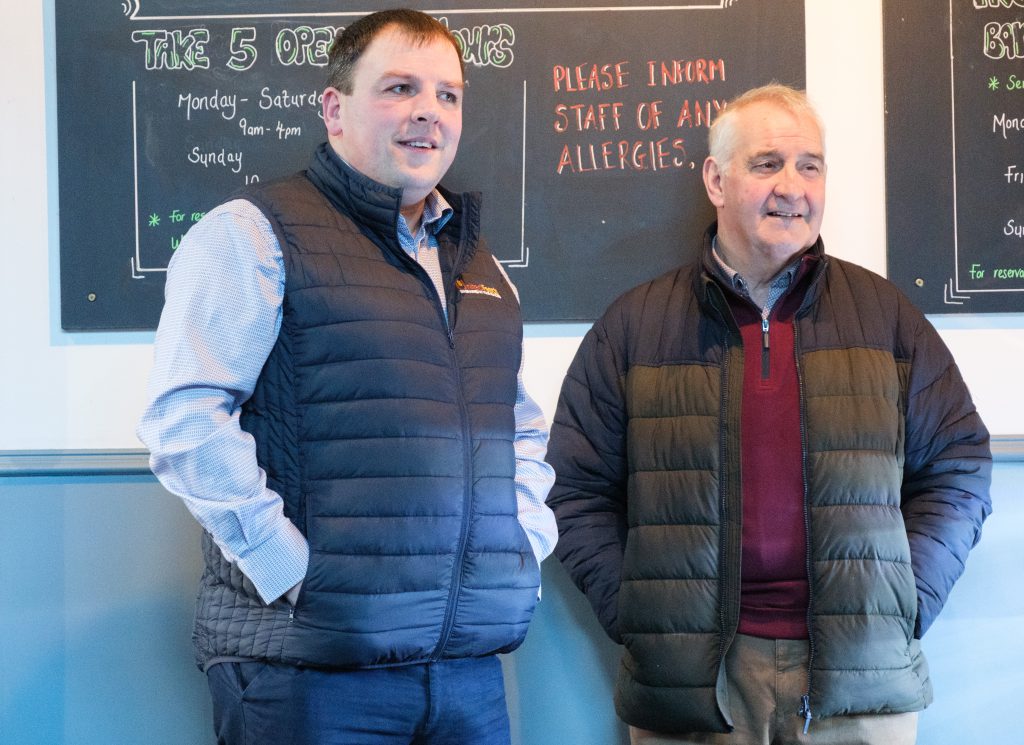 Two men beside each other, leaning on a wall.