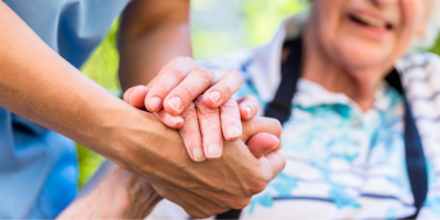 A nurse holding the hand of an elderly patient