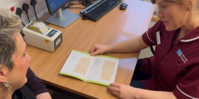 A nurse looking through a booklet with a woman.