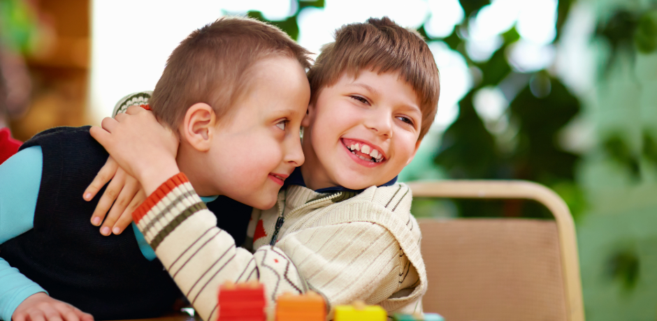 Two young boys, hugging each other.