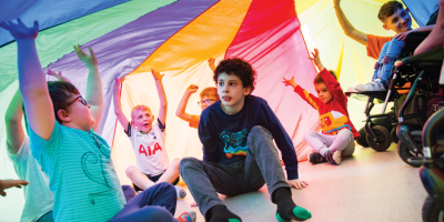 Group of boys and girls playing under multi-coloured tent