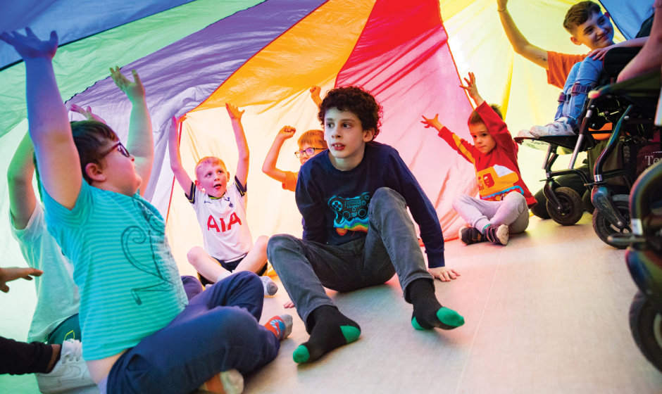 Group of boys and girls playing under multi-coloured tent