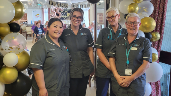 Four care workers standing in front of a balloon display.
