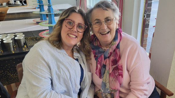 Two women sitting close to each other, smiling.