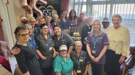 A large group of people standing with balloons and buns.