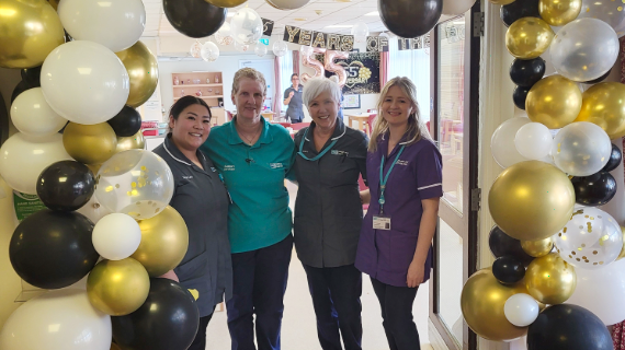 Four healthcare workers standing in front of a balloon display.