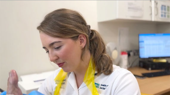 A podiatrist in a wite uniform working a person's feet.