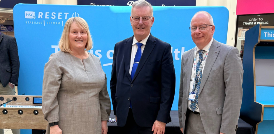 The Chief Executive of the Northern Trust stands with the Health Minister Mike Nesbitt and another man, with a This is our Health backdrop.
