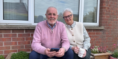 Man and woman sitting on garden seat.