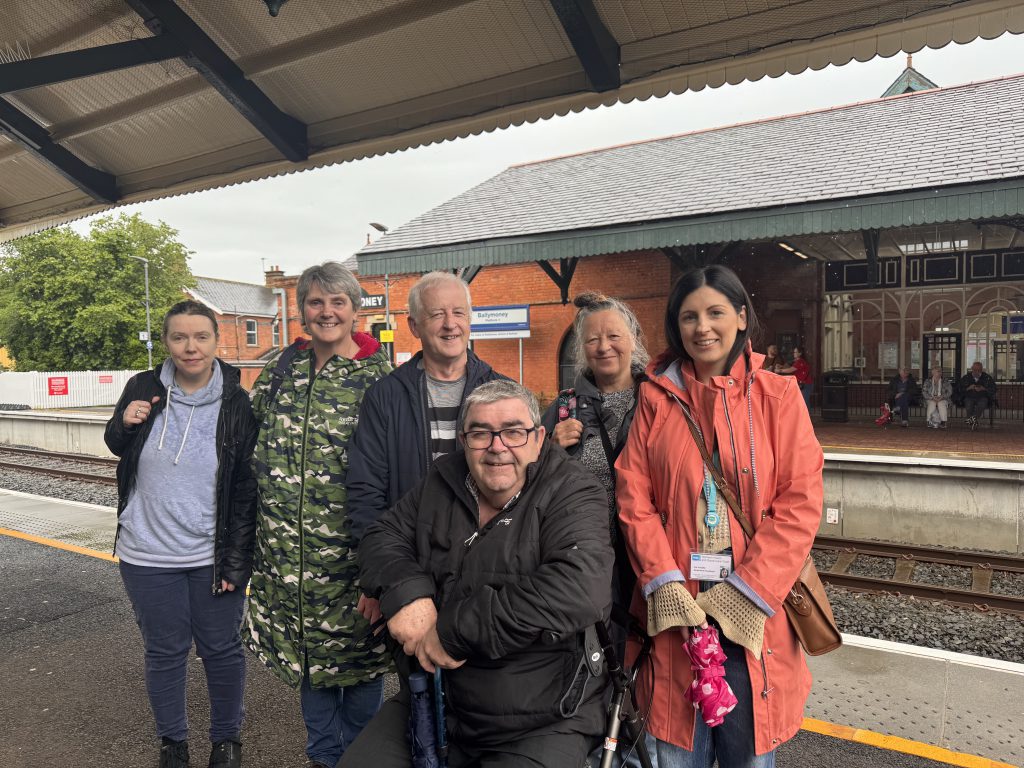 A group of people standing on the platform at Ballymoney station.