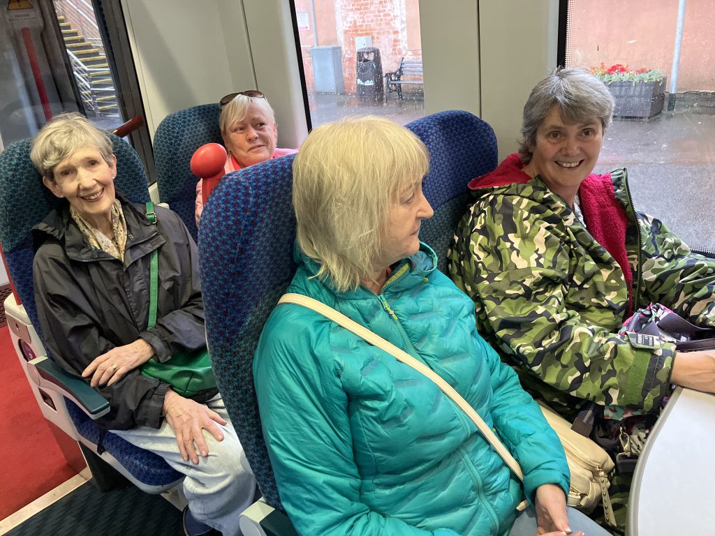 Four women pictured on board a train, sitting two by two.