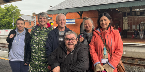 A group of people standing on the platform at Ballymoney station.