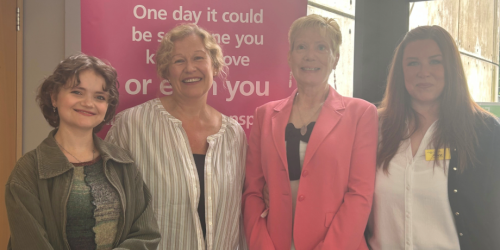 Four women standing together, with an organ donation pop-up banner behind them.