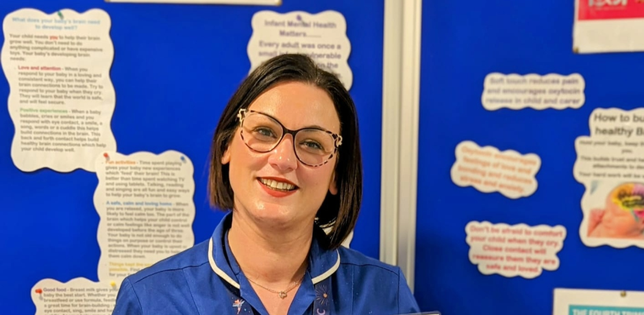 Neonatal Clinical Sister Leanne Richmond stands in front of an information board.