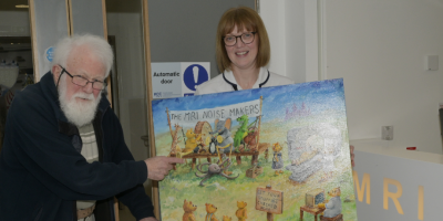 Artist Brian Willis stands beside radiographer Lesley Thompson, who is holding the MRI Noisemakers painting.
