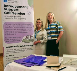 Two women stand beside a pop-up about bereavement support call service.