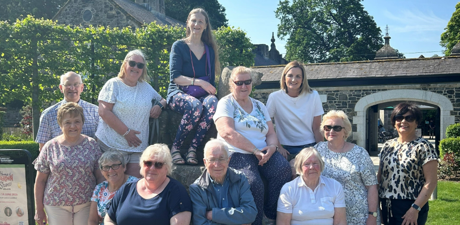 A group of people in Antrim Castle Gardens, sitting around a sculpture in the courtyard.