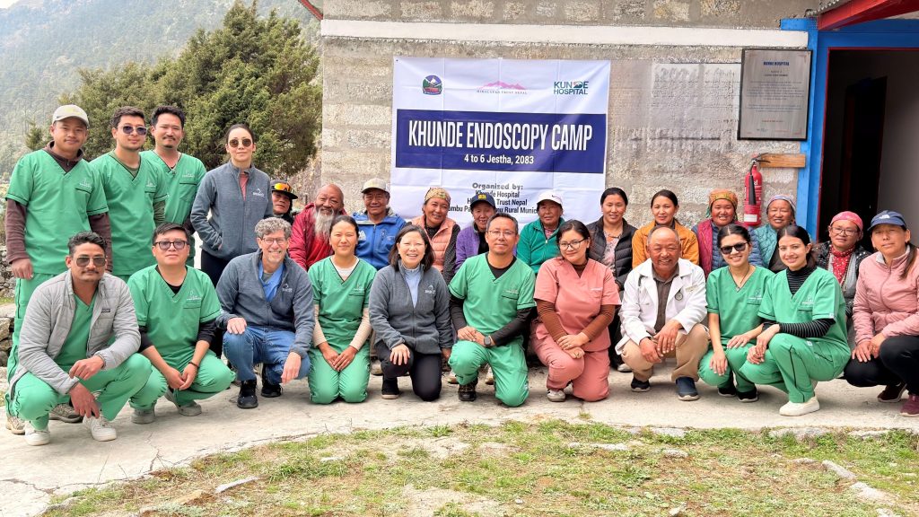 A group of medics and patients. Sign behind them reads Khunde Endoscopy Camp.