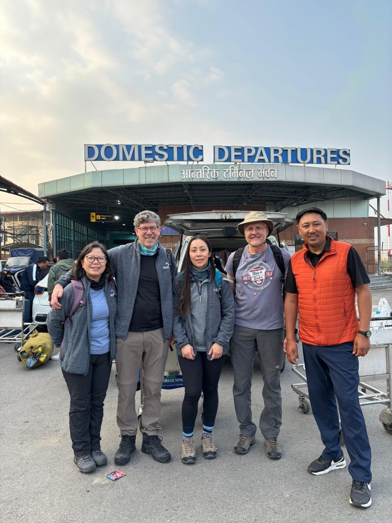 Five people standing at a domestic airport terminal.
