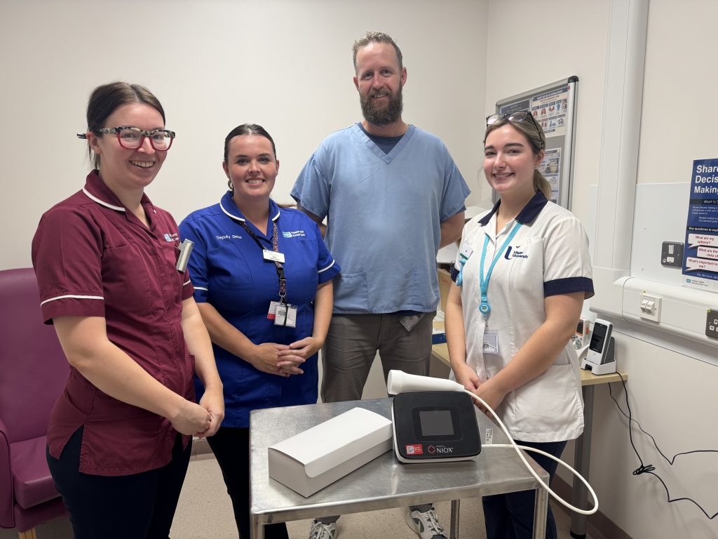 Four healthcare workers standing together, smiling, in a clinical setting