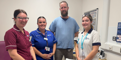 Four healthcare workers standing together, smiling, in a clinical setting.