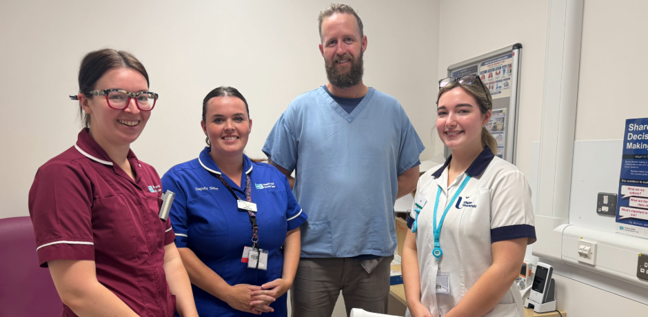 Four healthcare workers standing together, smiling, in a clinical setting.