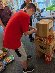 A service user builds a robot shape using cardboard boxes.