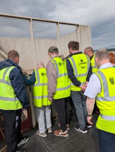 A group of service users wearning high-viz vests standing together at a recycling centre.