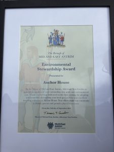 A framed certificate, referencing an Environmental Stewardship Award presented to the Anchor House team.