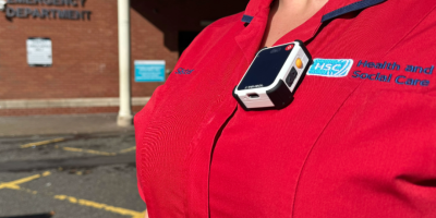A body worn camera attached to a red tunic.