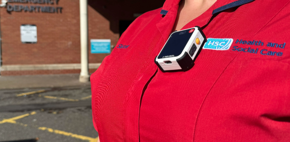 A body worn camera attached to a red tunic.