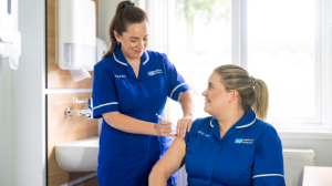 Healthcare worker receiving a flu vaccine from a colleague